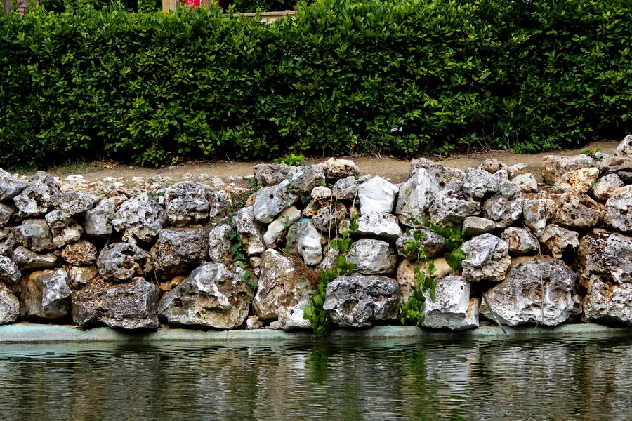 A dry-stacked stone retaining wall beside a water feature